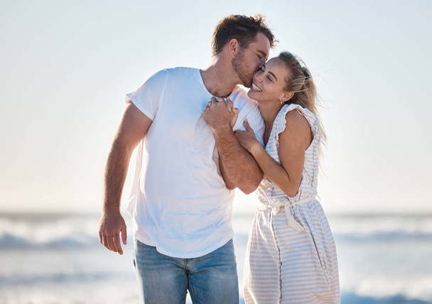 Szczęśliwy, miłość i para na plaży podczas wakacji na romans, miesiąc miodowy lub relaks. Szczęście, pocałunek i młody mężczyzna i kobieta spacerujący nad oceanem podczas romantycznej wakacyjnej przygody razem. - Zdjęcie, obraz