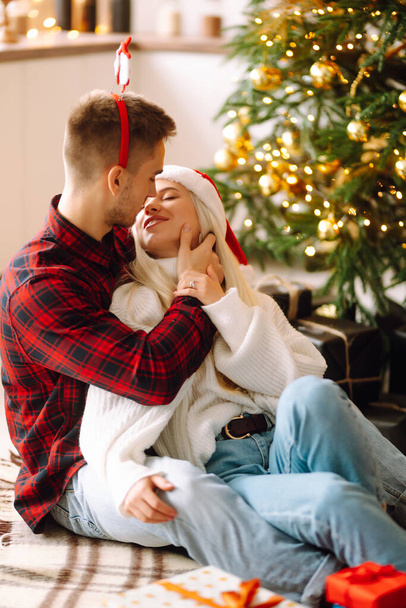 Young couple kissing over Christmas tree. Happy couple have Christmas surprise for holiday. Romantic day. Winter holidays. - Photo, image