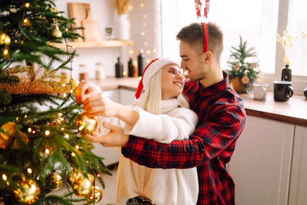 Young couple kissing over Christmas tree. Happy couple have Christmas surprise for holiday. Romantic day. Winter holidays. - Fotoğraf, Görsel