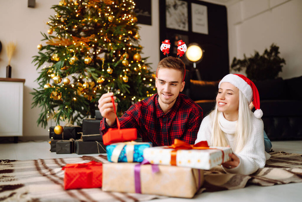 Young couple kissing over Christmas tree. Happy couple have Christmas surprise for holiday. Romantic day. Winter holidays. - Fotoğraf, Görsel