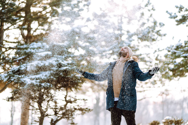 Un joven en un bosque nevado de invierno. Temporada, Navidad, viajes y concepto de personas. - Foto, Imagen