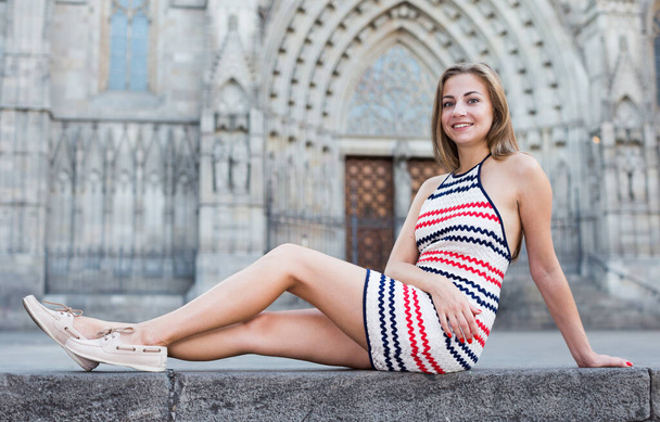 Young woman is posing sitting in striped dress in old city. - Photo, Image