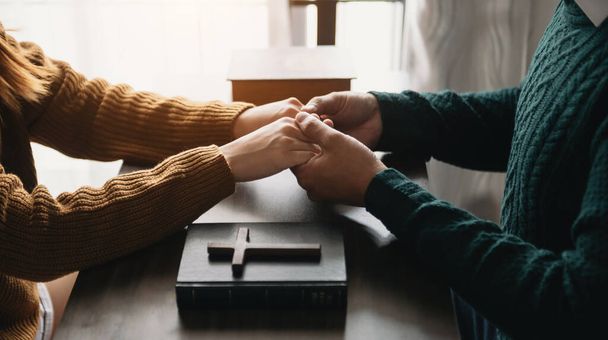 man and woman holding hands. cross and bible book on table  - Photo, image