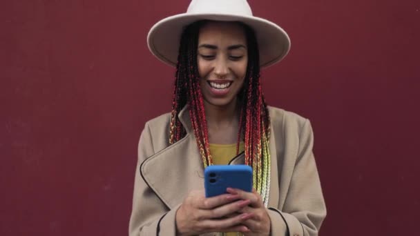 Heureuse jeune fille africaine s'amuser à l'aide d'un smartphone mobile extérieur - Séquence, vidéo