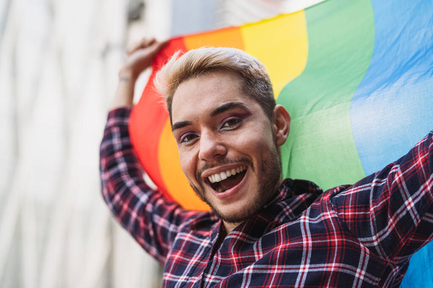Счастливый гей, празднующий прайд-фестиваль с радужным флагом ЛГБТК - Фото, изображение