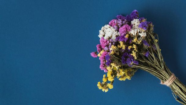 Buquê de flores silvestres secas multicoloridas em um fundo azul. Deitado. Espaço para cópia. Modelo para um cartão de saudação - Foto, Imagem