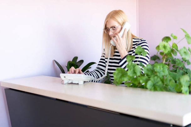 Mulher de meia-idade atraente fala ao telefone em seu local de trabalho - Foto, Imagem