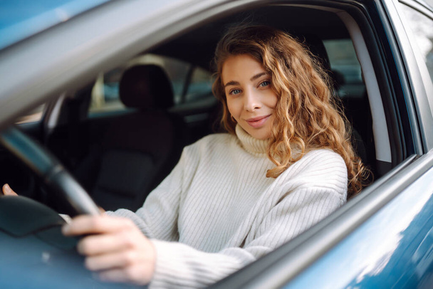 Young woman driving a car in the city. Car sharing, rental service or taxi app. - Fotó, kép