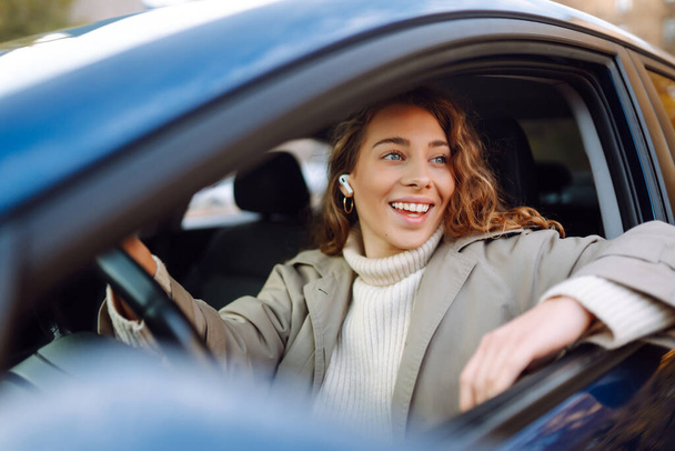 Young woman driving a car in the city. Car sharing, rental service or taxi app. - Fotó, kép