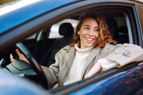 Young woman driving a car in the city. Car sharing, rental service or taxi app. - Zdjęcie, obraz