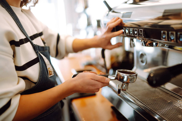 Barista holding cup getting fresh coffee that being brewed by the machine in cafe. Professional coffee brewing. - 写真・画像