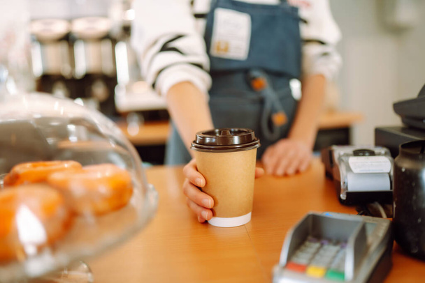 Smiling barista- girl giving take away coffee cups to a customers.   - Zdjęcie, obraz