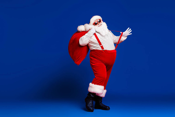 Pleine longueur taille du corps vue de son il attrayant enfantin joyeux gai drôle graisse Père Noël portant grand sac avoir du plaisir à danser isolé lumineux vif éclat vibrant fond de couleur rouge. - Photo, image