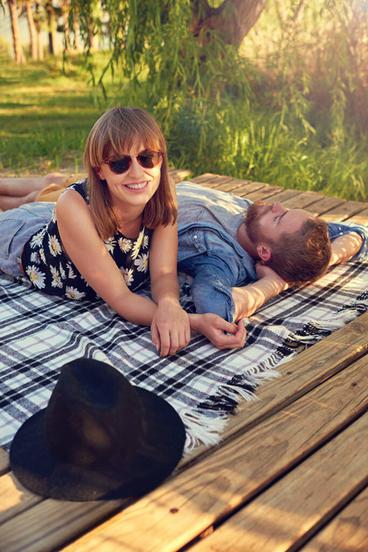 Des journées d'été sans soucis. un jeune couple affectueux couché sur une couverture à l'extérieur - Photo, image
