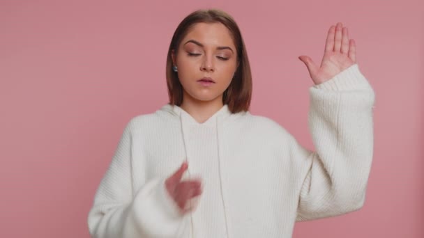 I swear to be honest. Sincere responsible young woman raising hand to take oath, promising to be honest and to tell truth, keeping hand on chest. Caucasian girl isolated on studio pink background - Footage, Video