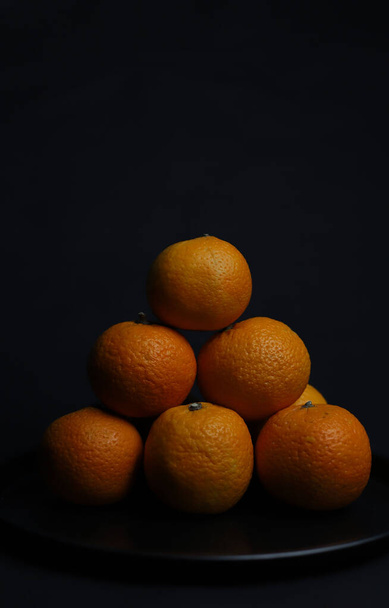 dulce naranja ronda jugosa mandarinas enteras se encuentran sobre un fondo negro ronda negro tray.for postales pancartas folletos invitaciones - Foto, Imagen