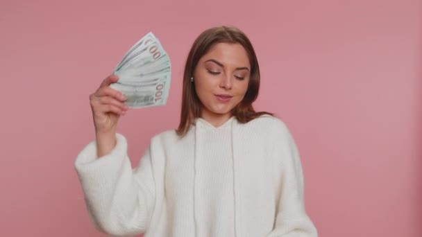 Багаті задоволені босом тисячоліття жінка махає грошима доларових грошових купюр, таких як фанат, успішна бізнес-кар'єра, переможець лотереї, великий дохід, багатство. Молода дівчина ізольована на рожевому студійному фоні
 - Кадри, відео