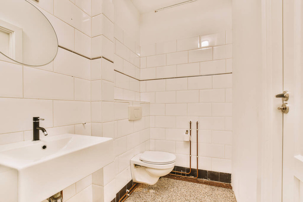 Флеш туалет расположен между раковиной и душем в небольшой кафельной ванной комнаты современной квартиры - Фото, изображение