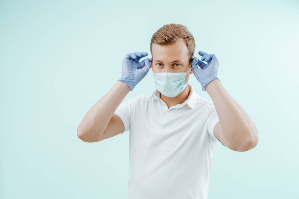 Врач снимает медицинскую маску в клинике на светло-голубом фоне. Здоровое понятие - Фото, изображение