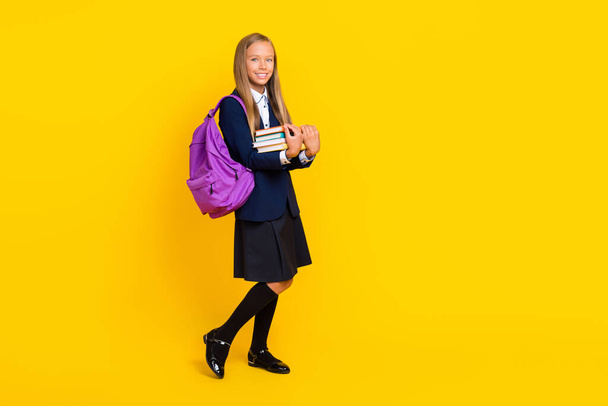 Full photo of lovely clever schoolgirl with long hairstyle wear blue blazer hold exercise book isolated on yellow color background. - Fotó, kép