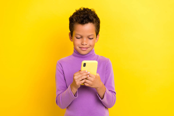 Photo portrait of cute little pupil boy hold device typing sms friend roaming wear trendy violet outfit isolated on yellow color background. - Foto, Imagem
