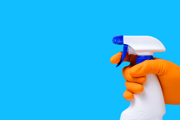 Sprayer for cleaning windows and plumbing in hand with glove on blue background - Photo, image