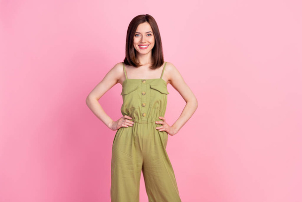 Photo of nice lovely positive confident woman with bob hairstyle dressed khaki overall hands on waist isolated on pink color background. - Foto, immagini