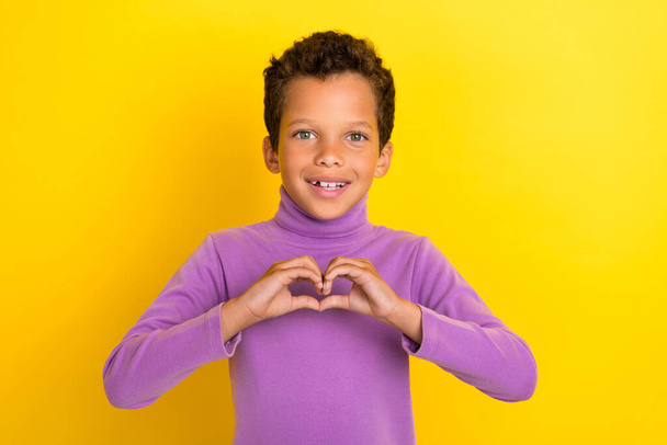 Portrait of cheerful cute boy arms fingers showing heart gesture isolated on yellow color background. - Foto, afbeelding