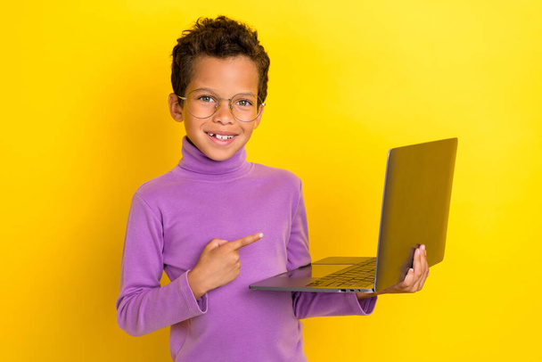 Portrait of little person toothy smile indicate finger wireless netbook isolated on yellow color background. - Foto, Bild