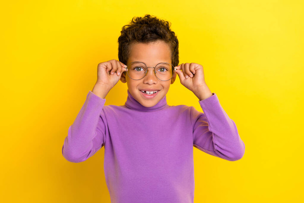 Portrait of cheerful smart schoolchild hands touch glasses toothy smile isolated on yellow color background. - Foto, afbeelding