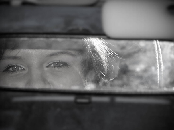 Bellissimi occhi di una ragazza nello specchietto retrovisore di una macchina. Foto in bianco e nero - Foto, immagini