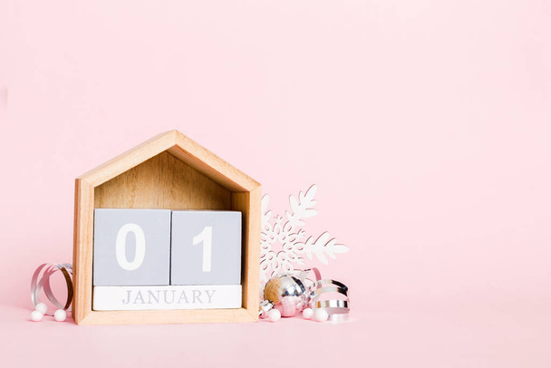 1 january. Christmas composition on colored background with a wooden calendar, with a gift box, toys, bauble copy space. - Фото, изображение
