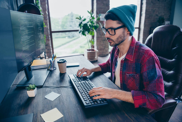 Photo of intelligent serious guy dressed eyewear typing code modern device keyboard indoors workstation workshop home. - Фото, изображение