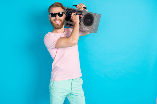 Photo portrait of nice young man hold vintage boombox volume up music loud wear trendy pink outfit isolated on cyan color background. - Photo, Image