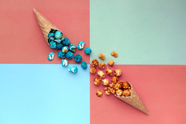 вафельний конус морозива з розливом попкорну на теракоті барвистий фон. Блакитна і карамельна фаст-фуд закуски курукопії. Вид зверху яскравий фон хіпстера
. - Фото, зображення