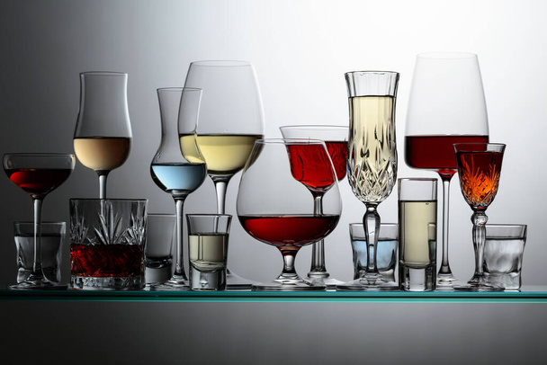 Різні алкогольні напої в барі на скляних полицях
. - Фото, зображення