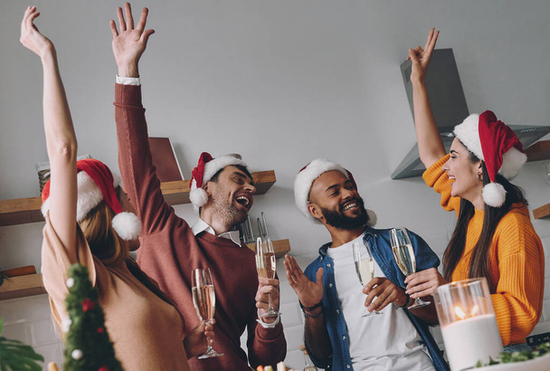 Group of young people having fun while enjoying Christmas dinner at home together - Foto, Bild