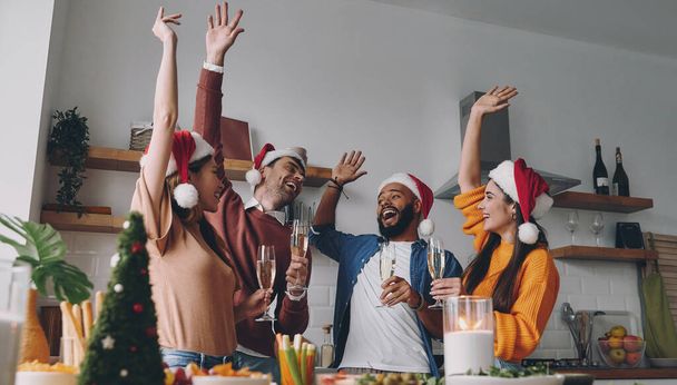 Group of young people having fun while enjoying Christmas dinner at home together - Foto, afbeelding