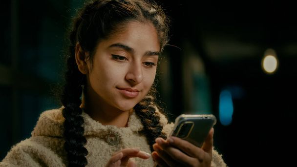 Arabský koncentrovaný dívka spotřebitel nakupující uživatel mladý bruneta středovýchodní žena stojí ve večerních hodinách město textové zprávy na mobilní telefon gadget nakupování on-line rezervace dodání scroll internet novinky - Fotografie, Obrázek