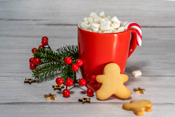 Pain d'épice homme et une tasse rouge de chocolat chaud avec guimauves sur table blanche, et décoration de Noël  - Photo, image