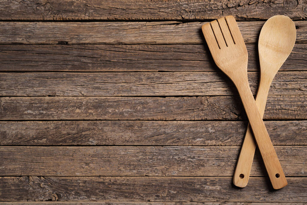Crossed wooden spoon and fork on a background of old rustic wooden slats. - Valokuva, kuva