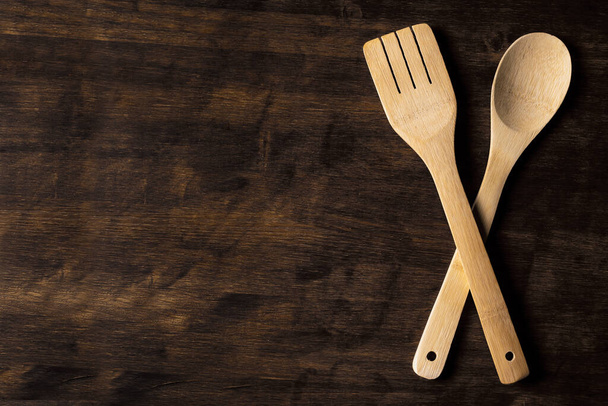 Crossed wooden spoon and fork on an old rustic wooden background. - Фото, изображение