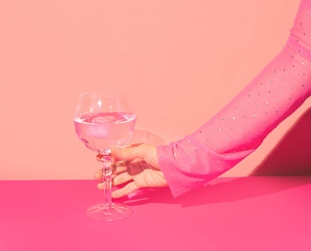 Pink gin cocktail in a highball glass and female hand against bright wall. Girls party idea.  - 写真・画像
