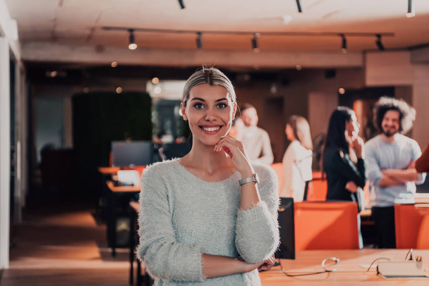 Portrait photo of a modern blonde on a break from work in a modern office. In the background, the team working on the projects.  - Φωτογραφία, εικόνα