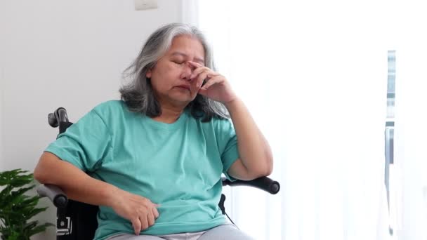 Азиатская пожилая женщина, сидящая в инвалидном кресле, страдает от стресса и депрессии. Жить одной дома. Концепция пожилых пациентов, депрессивные расстройства у пожилых людей. - Кадры, видео