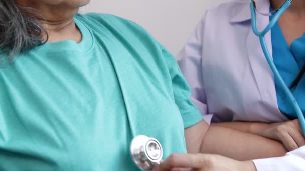 Aziatische vrouwelijke arts gebruikt een stethoscoop om oudere patiënten die lijden aan depressie te onderzoeken Ze zat in een rolstoel. Het concept van senior patiënten. Ouderen Health Care Center - Video