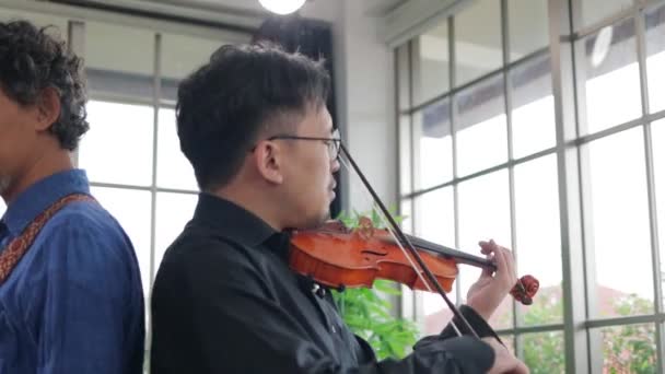Deux musiciens asiatiques jouent des instruments classiques violon et guitare électrique dans la salle de pratique. Concept de jouer de la musique live et du groupe. La musique joue dans le studio d'enregistrement. - Séquence, vidéo