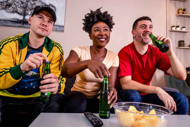 Amigos viendo un partido de fútbol en casa en la televisión, animando a su equipo nacional. Copa del mundo de fútbol.  - Foto, imagen