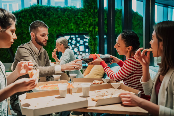 Eating pizza with diverse colleagues in the office, happy multi-ethnic employees having fun together during lunch, enjoying good conversation, and emotions. - Zdjęcie, obraz