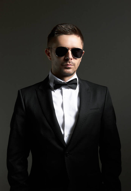 Man in zwarte suite met bril, op zwarte achtergrond - Foto, afbeelding
